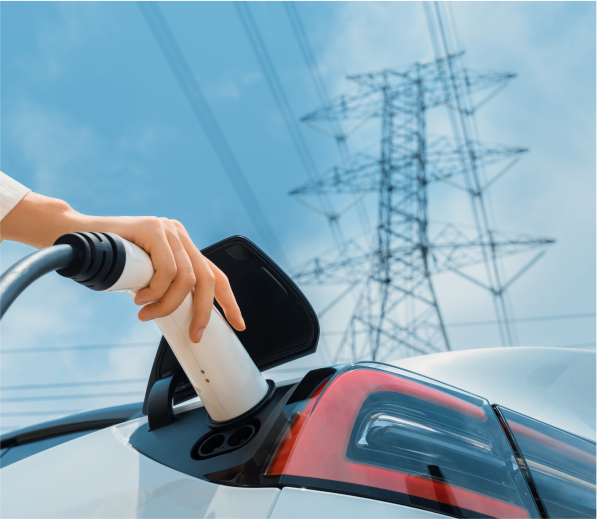 Person charging an electric vehicle at a public charging station.